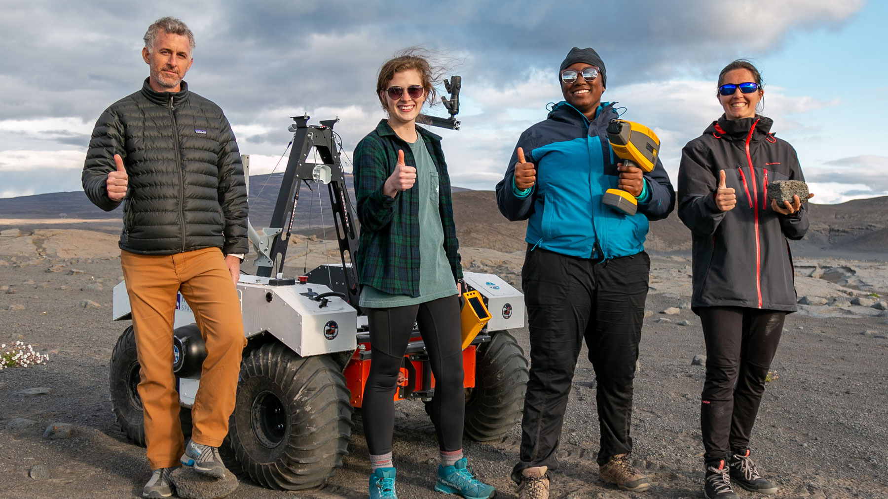 Diverse group of individuals in front of a replica Mars rover