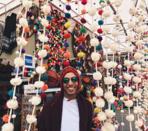 Student standing in front of traditional crafts. 