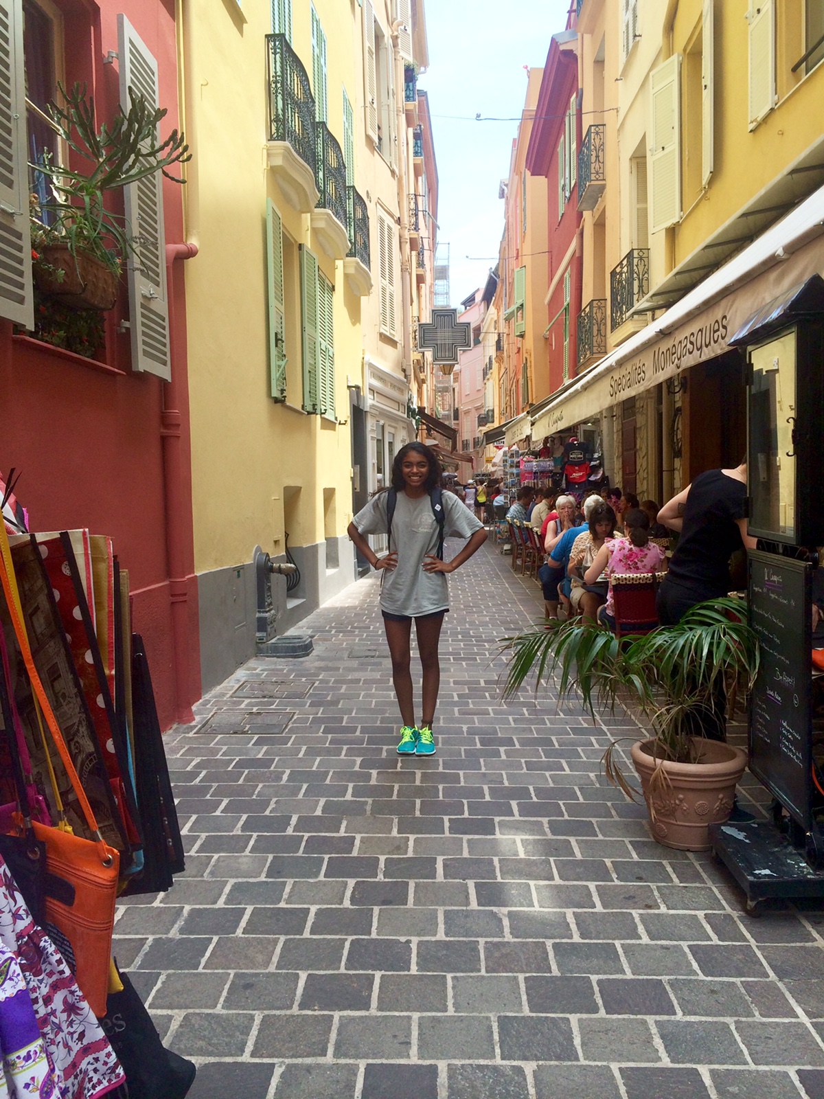 2019_Summer_Spain_Student_Shop_Facades Student standing in front of colourful shop facades on a narrow side street in Spain.