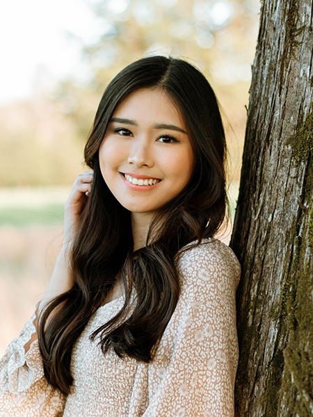 portrait of Madelaine Setiawan leaning against a tree