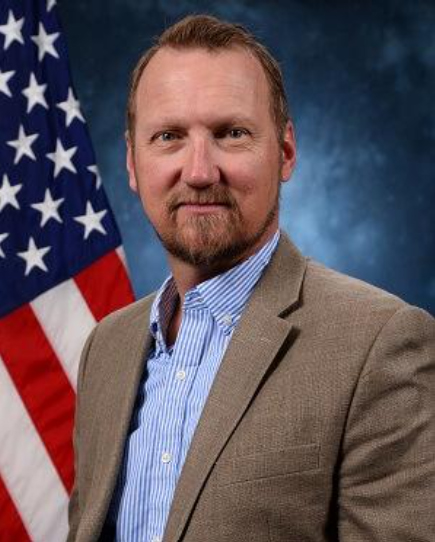 Portrait of Mark Grotelueschen in front of the American flag