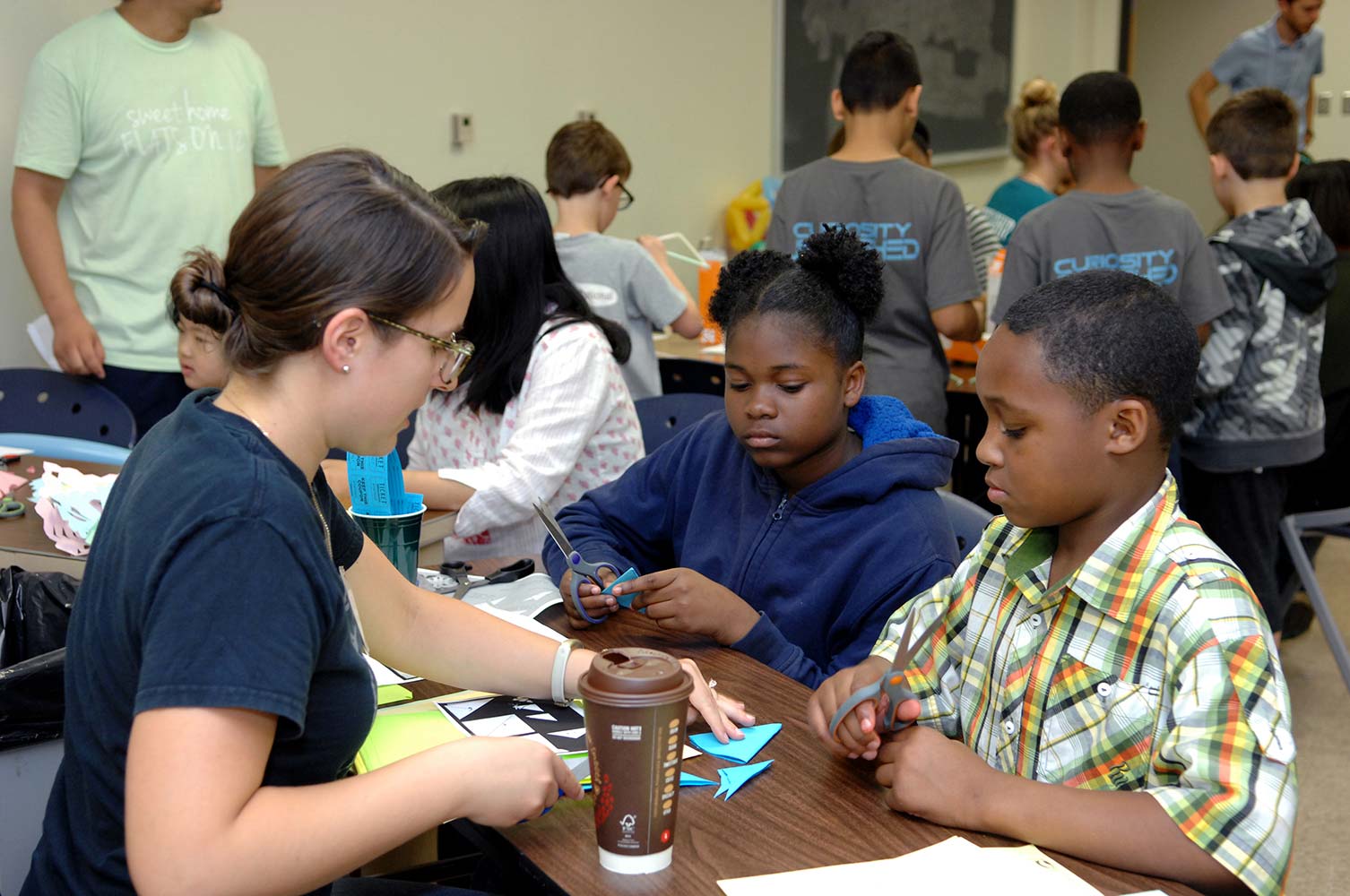 A group of young children complete a construction paper activity at the Math and Stat Fair