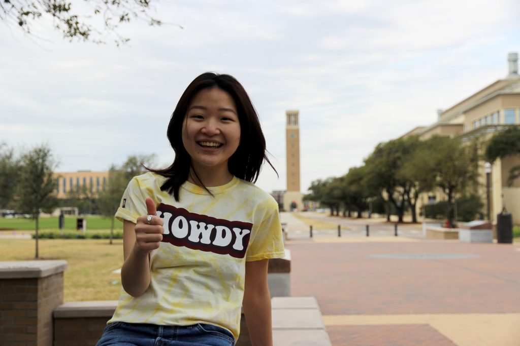 Girl posing with thumbs up on campus 