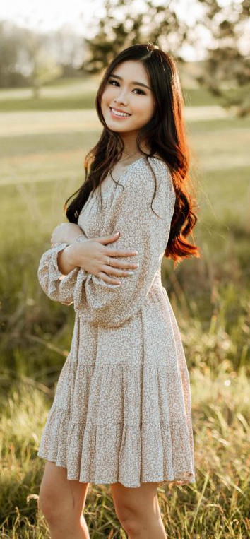 Madelaine standing with arms crossed in a field