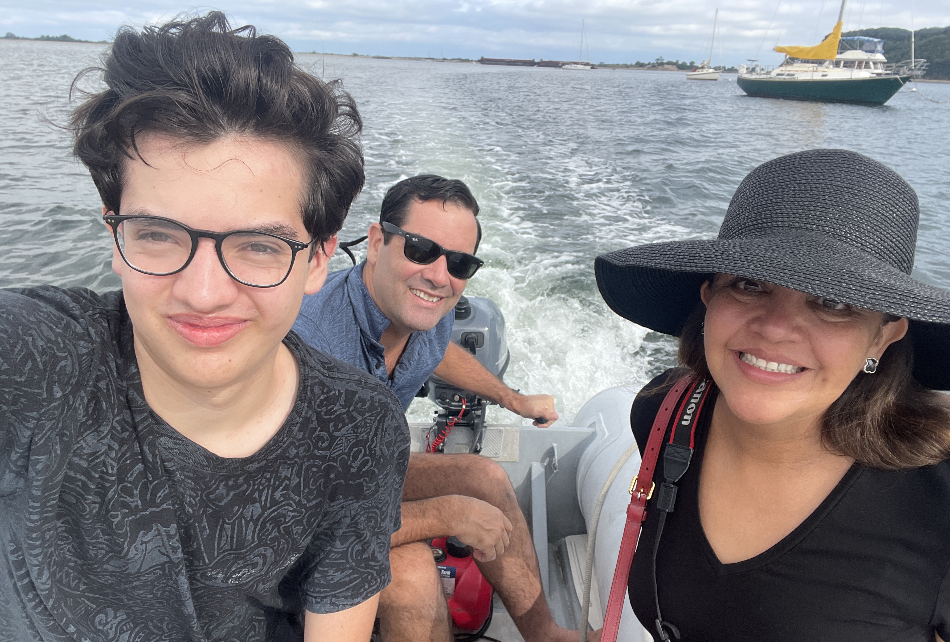 Texas A&amp;M former student Brett Graham steers the outboard motor of a boat, accompanied by his wife and son.