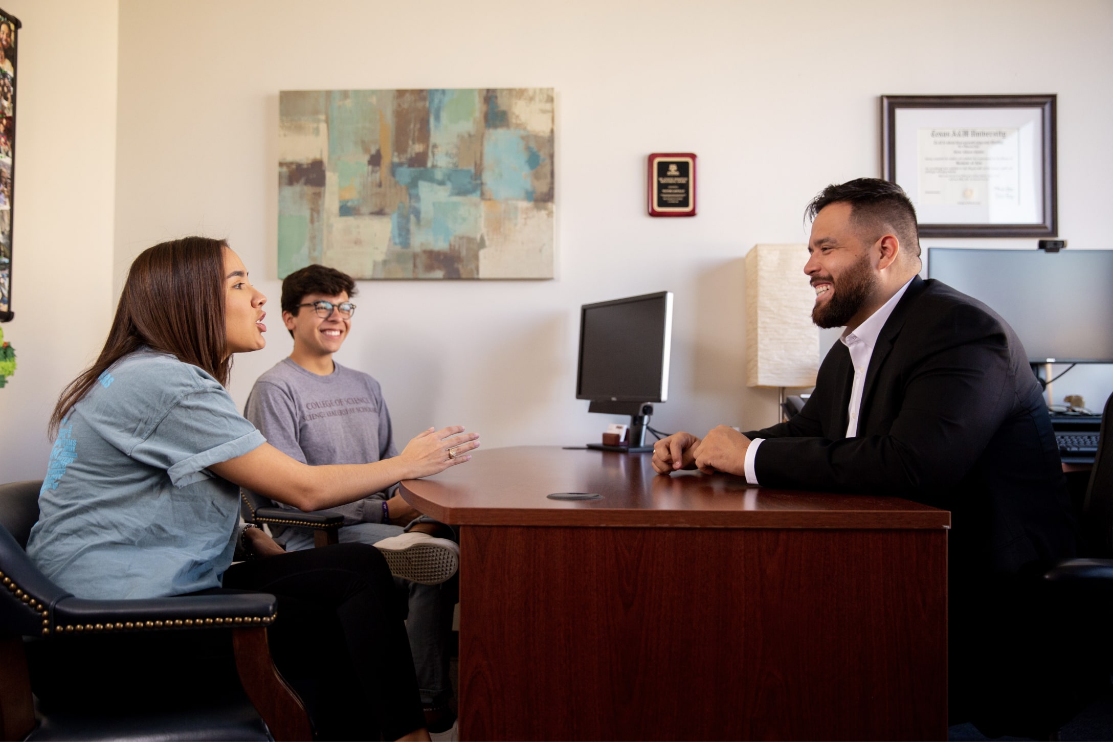 Texas A&amp;M Science Leadership Scholars Program academic advisor Victor Castillo visits with two students in his office within the John R. Blocker Building