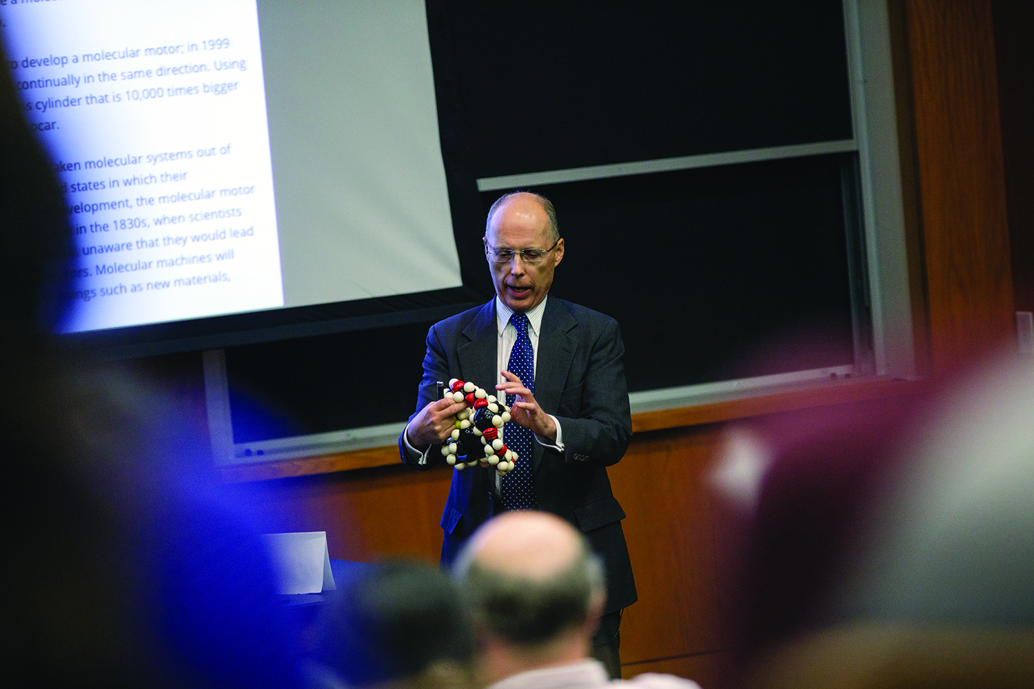 Texas A&amp;M chemist John Gladysz holds a 3-D DNA model while he lectures to a full auditorium