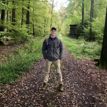 Tristan Krause smiles for the camera while standing on a tree-lined pathway during a dig in Germany