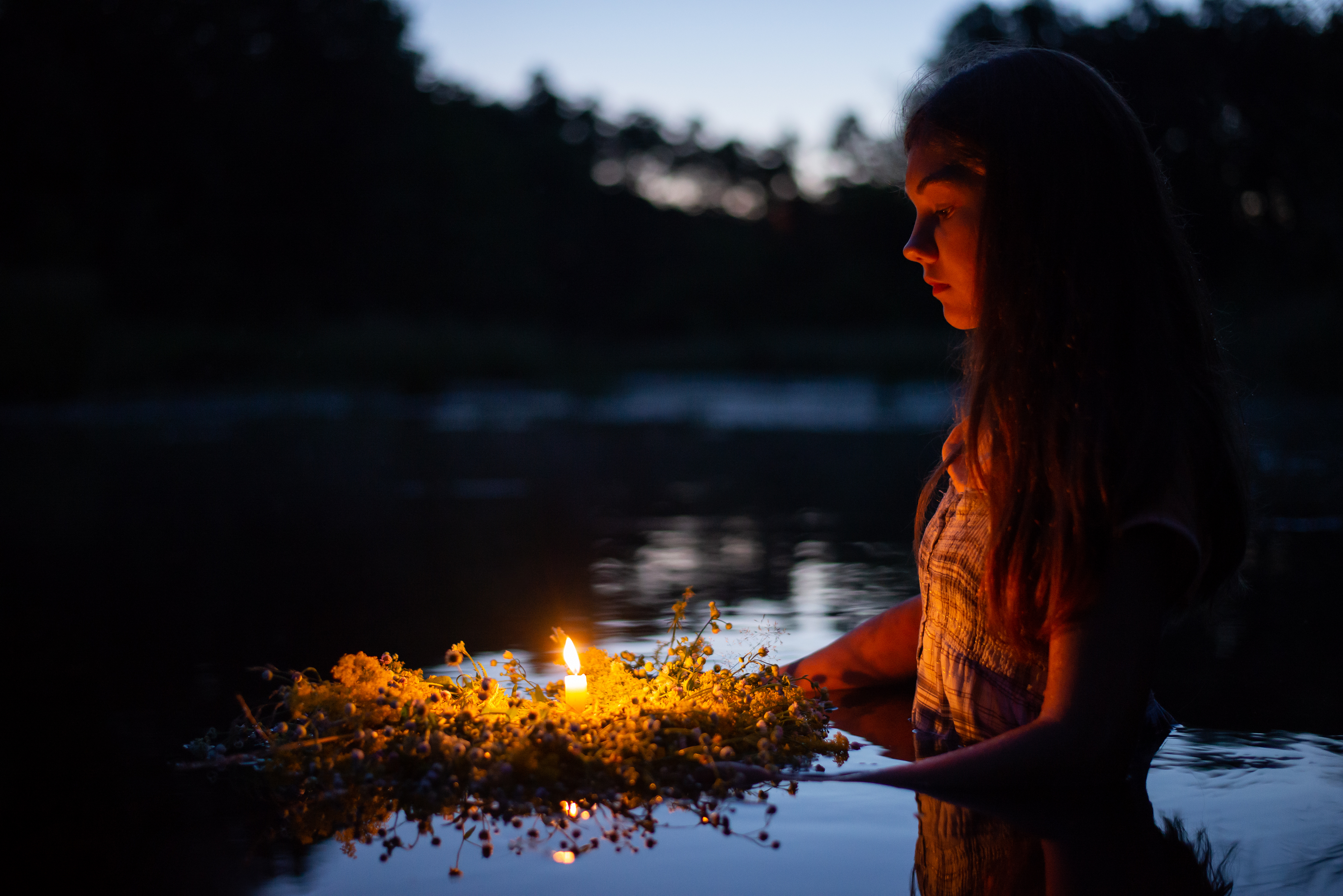 Portrait of a small girl in river late at night, set the wreath to float with a candle - stock photo