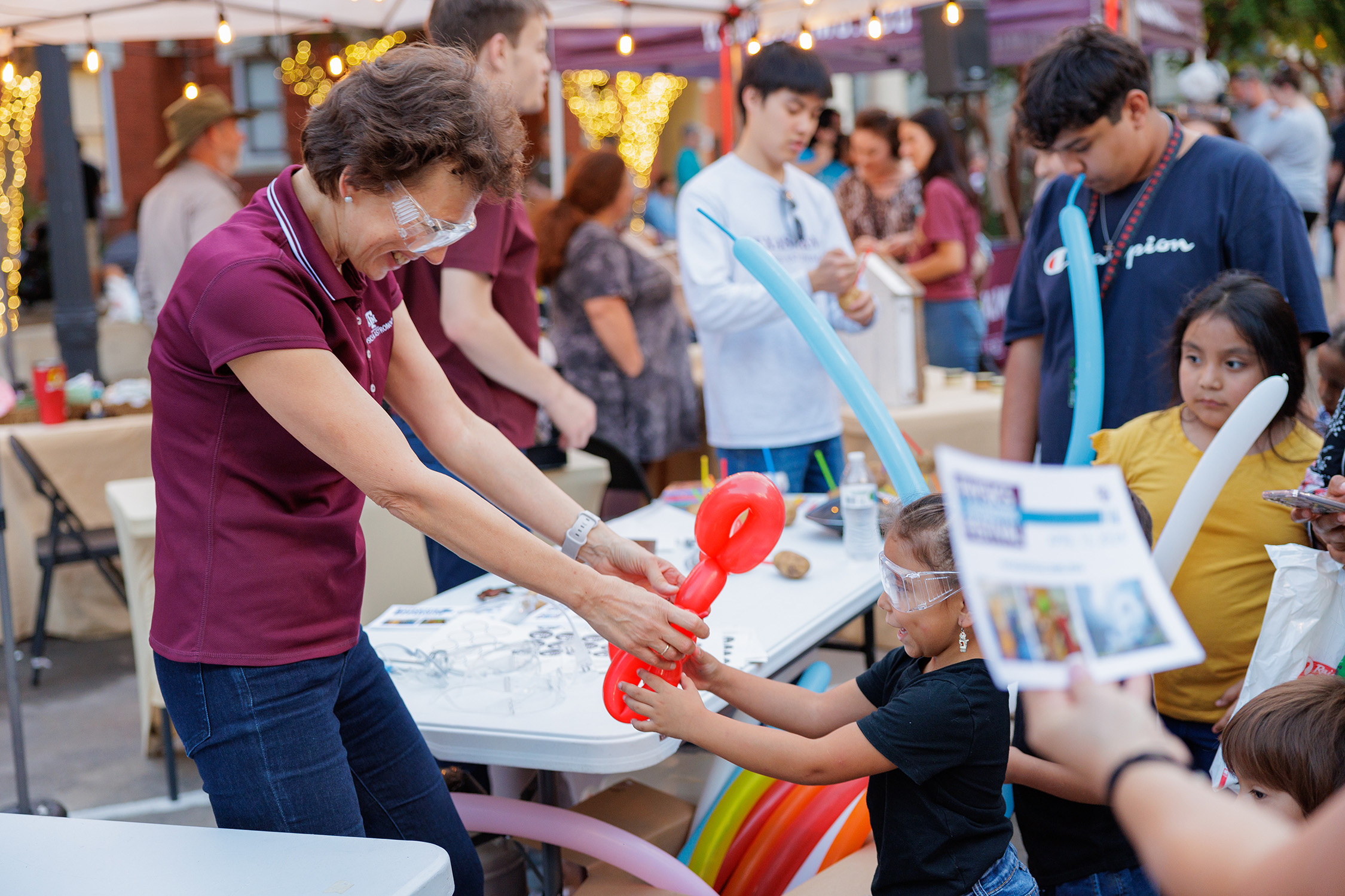 Texas A&amp;M physicist Tatiana Erukhimova makes a balloon animal for a young participant at First Friday at Downtown Bryan