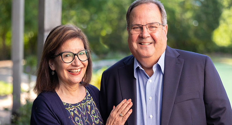 Rita and Dr. Kevin Gamache smile for the camera while posing in an outdoor setting