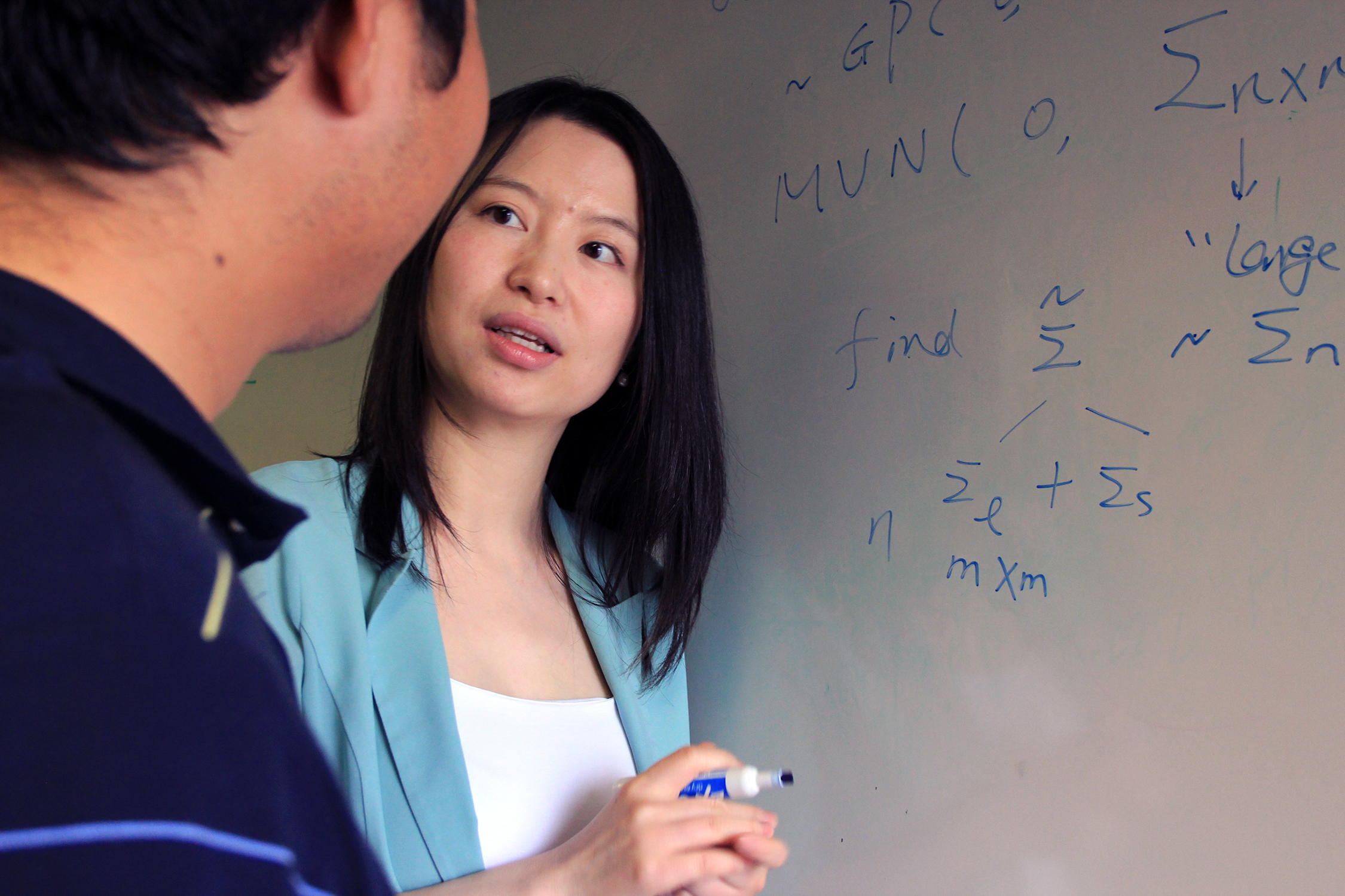 Texas A&amp;M University statistician Huiyan Sang writes formulas on a dry erase board and explains them to a student