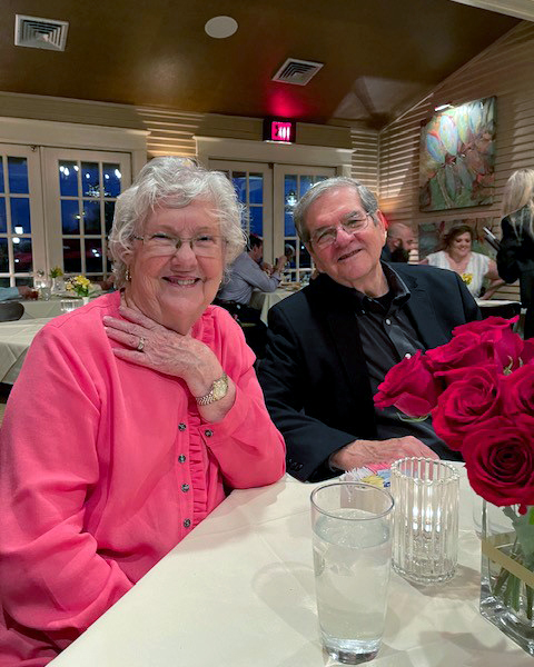 Texas A&amp;M University statistician Dr. William B. Smith and his wife Patricia Smith, sitting together at a dining table adorned with red roses