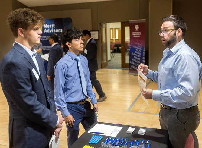 Two Texas A&amp;M University economics majors speak with a recruiter at the 2024 Economics Career Fair, held September 25 in the Memorial Student Center on the Texas A&amp;M campus