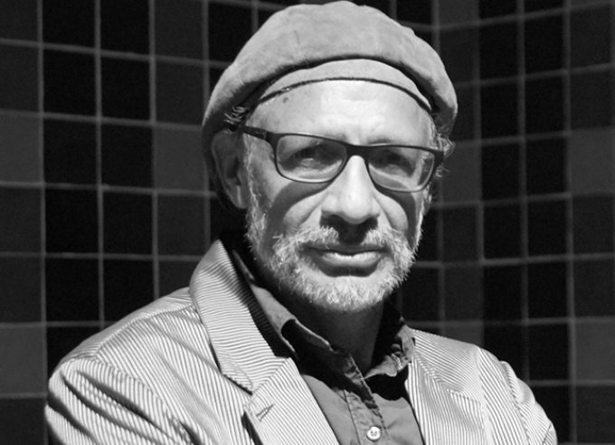 Black and white close-up headshot of man wearing a beret and sunglasses