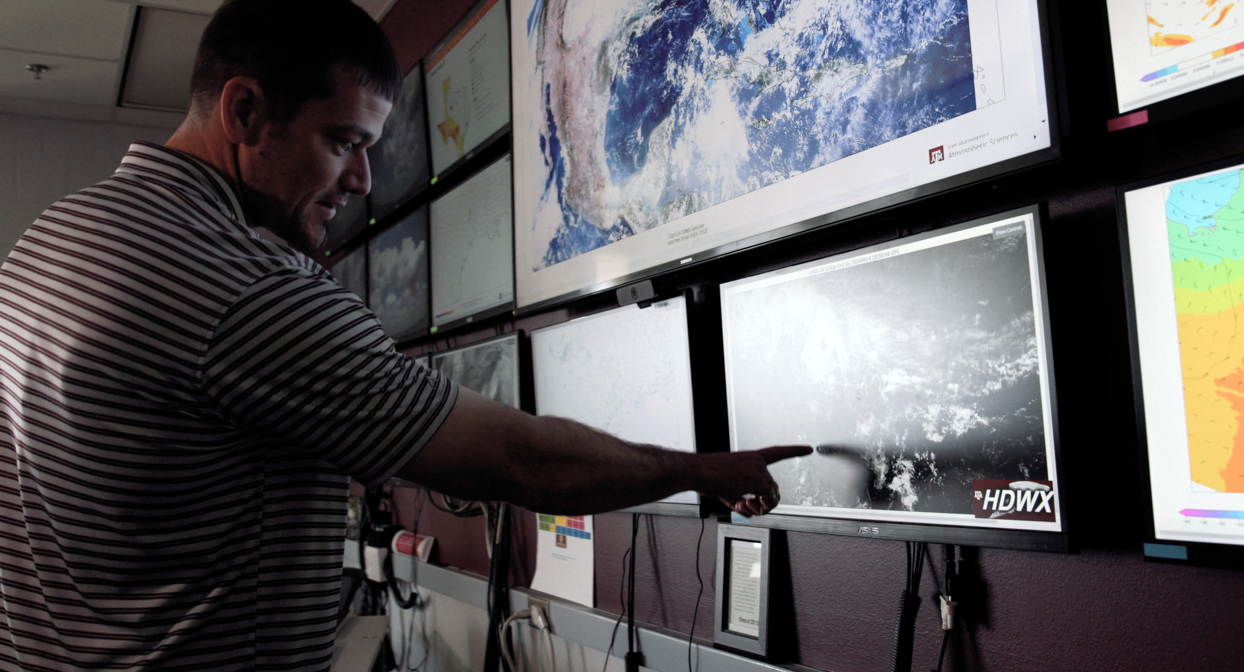 Texas A&amp;M University atmospheric scientist Eric Nielsen points to a monitor on the wall within the Texas A&amp;M Weather Center in the Department of Atmospheric Sciences