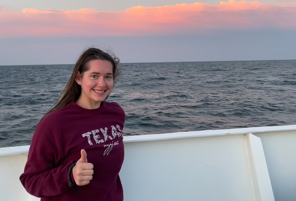 Kailey Rettmann giving a thumbs up aboard a recent Texas A&amp;M Oceanography Schade Cruise at sunset with a "Texas A&amp;M" sweatshirt on.