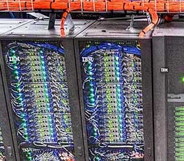 two racks of server computers connected to a bundle of network cables neatly arranged in a cable rack. The server racks have the IBM logo on the front.